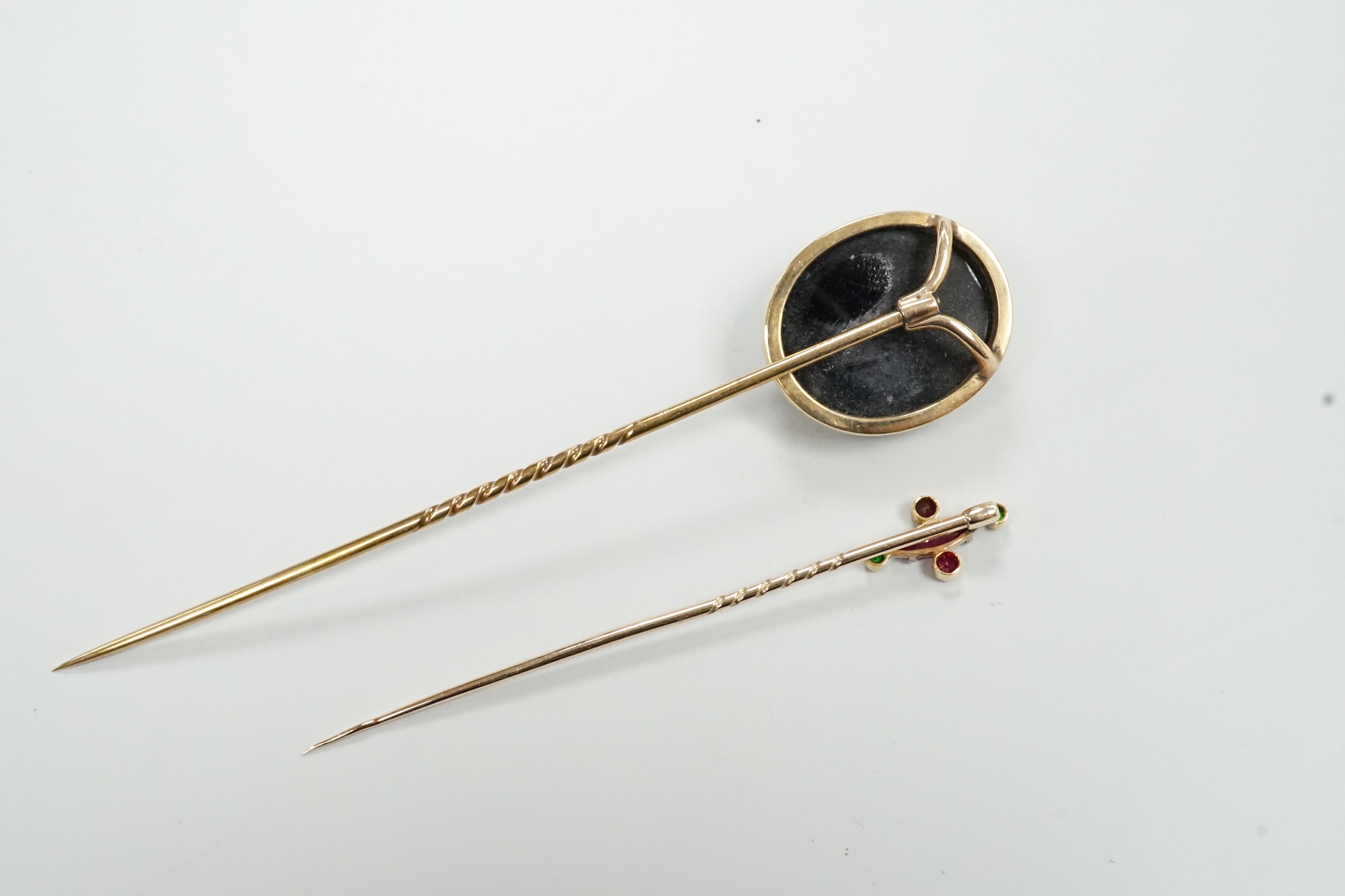 A yellow metal and sardonyx cameo stick pin, 91mm and one other gem set stick pin.